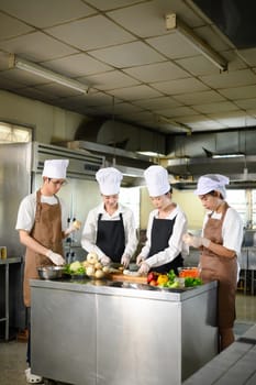 Young chefs practice slicing vegetables during a hands on cooking class at culinary school.