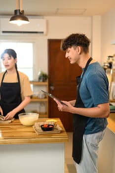 Young couple preparing pancake batter together in a cozy kitchen.