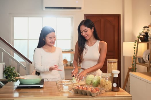 Smiling mother and daughter preparing a healthy meal together in a cozy kitchen at home.