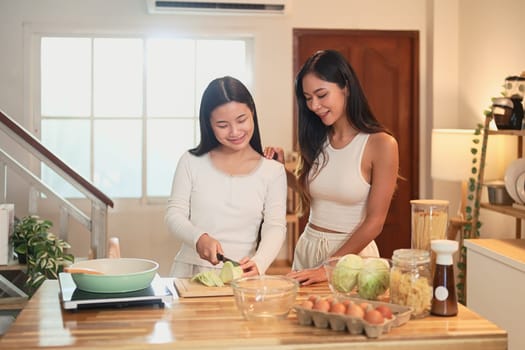 Smiling mother and daughter preparing a healthy meal together in a cozy kitchen at home.