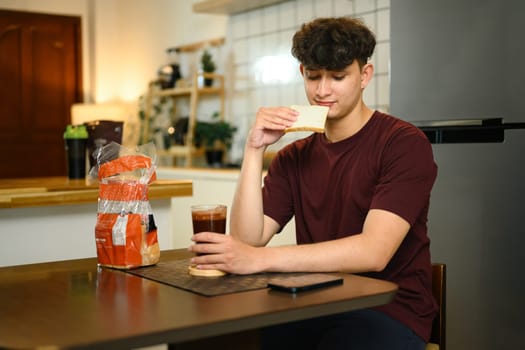 Casual morning routine of man having bread and drink in a cozy kitchen.