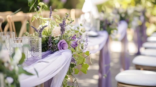 Elegant wedding dining table with candles floral arrangements in shades of purple, lavender and pink in a garden
