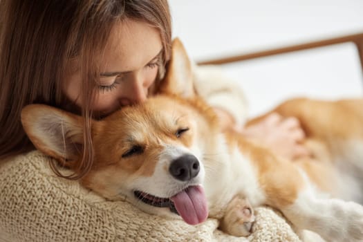 Happy Corgi dog sleeping peacefully in woman's arms, cozy warm hug, showing love, trust, and relaxation.