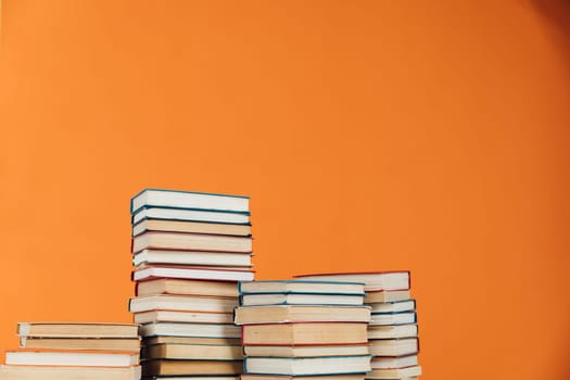 Stacks of old educational books for learning on an orange background