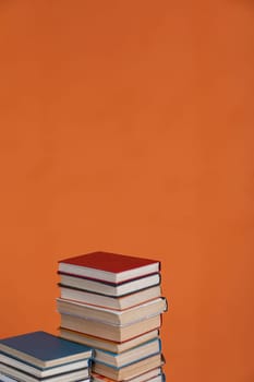Stacks of old educational books for learning on an orange background