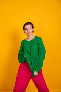 40-year-old woman in green knitted sweater on yellow background