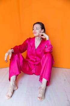 40 year old woman in crimson silk pajamas sitting on the floor