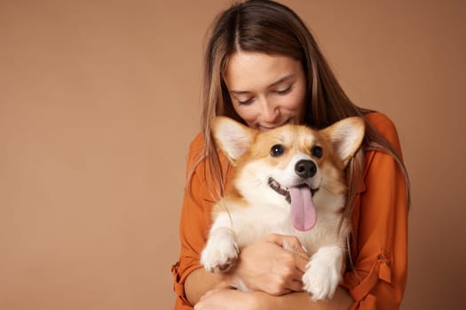 Smiling young woman hugging happy Corgi dog with tongue out, expressing love, affection, and pure joy.