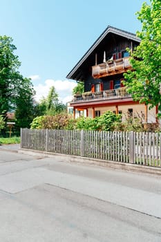 In Strobl, Upper Austria, a charming traditional house stands amidst lush greenery. The well-maintained property features a balcony and a wooden fence, embodying local architectural style.