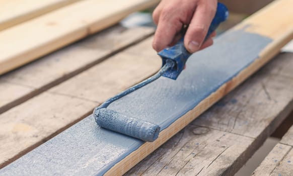A man paints a board with paint. Selective focus. People.