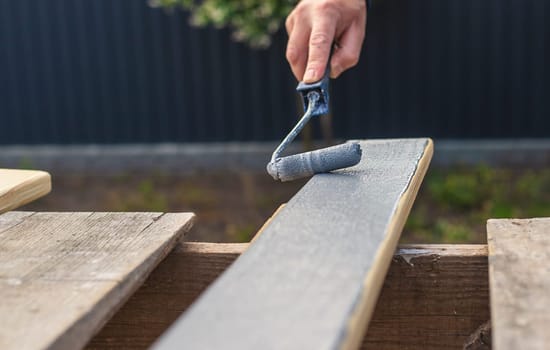 A man paints a board with paint. Selective focus. People.