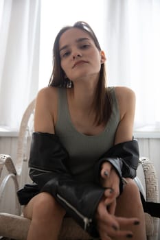 Portrait of a beautiful fashionable brunette woman in a leather jacket on a gray background