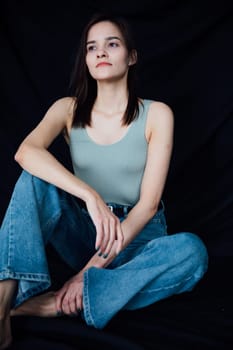 Slim fashion woman in jeans and gray t-shirt on black background