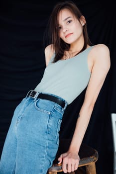 Slim fashion woman in jeans and gray t-shirt on black background