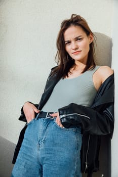 Fashionable brunette woman posing in jeans and black leather jacket