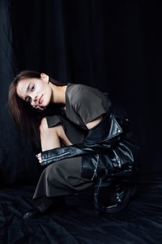 Portrait of Beautiful Fashion Brunette Woman in Gray Dress and Leather Jacket on Black Background