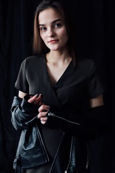 Portrait of Beautiful Fashion Brunette Woman in Gray Dress and Leather Jacket on Black Background