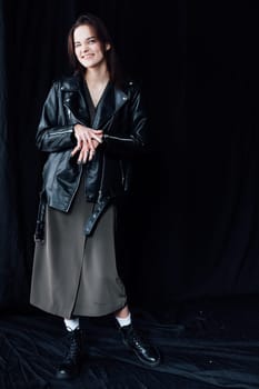 Portrait of Beautiful Fashion Brunette Woman in Gray Dress and Leather Jacket on Black Background