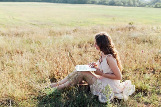 Woman relaxing in rural field and chatting on laptop online