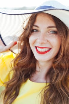 Beautiful woman in big hat smiling with red lipstick