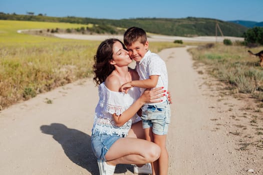 Mother with young son walking in a rural field in summer by the road