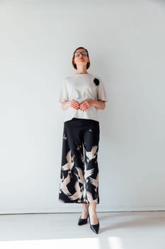 Portrait of a beautiful fashionable woman of 40 years old in the interior of a white room