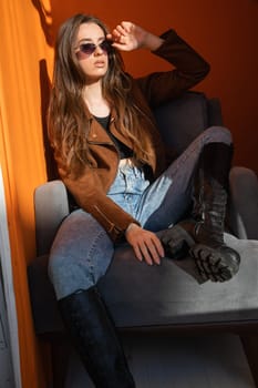 Beautiful woman in sunglasses in orange room by window