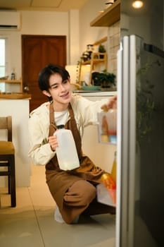 Man wearing an apron grabbing ingredients to prepare breakfast at home.