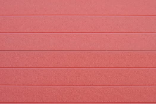 Close up of red corrugated metal sheet creating repeating textured pattern, garage door detail, durable and corrosion resistant cladding material,