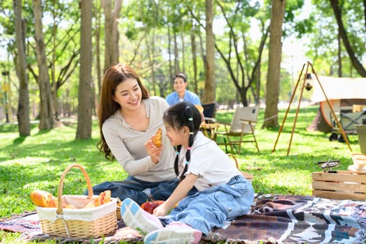 Mother and daughter sharing food during a family camping trip.