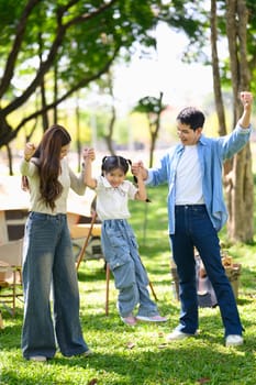 Happy family enjoying quality time together at a forest campsite with tents and picnic setup.