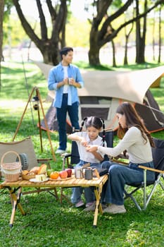 Mother and daughter enjoying a relaxing breakfast at a campsite.