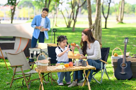 Mother and daughter enjoying a relaxing breakfast at a campsite.