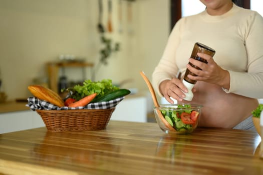 Pregnant woman preparing a fresh vegetable salad in the kitchen.