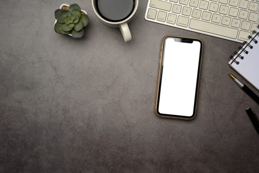 Flat lay of smartphone with blank screen on dark modern desk.