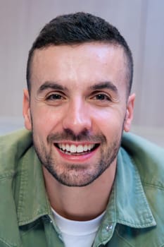 Portrait confident young caucasian man smiling at the camera in stylish and bright kitchen interior, suggesting a relaxed and welcoming home atmosphere with visible food and cooking elements.Vertical