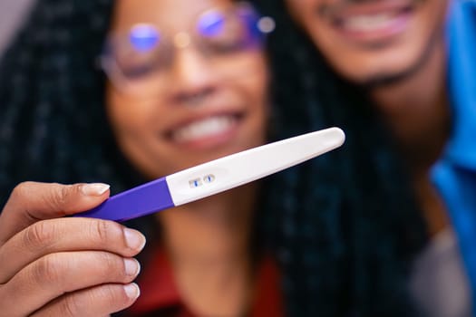 Close-up of a joyful couple smiling while holding a positive pregnancy test, celebrating the exciting news of expecting a baby. Concept of happiness, love, and new beginnings in family life.