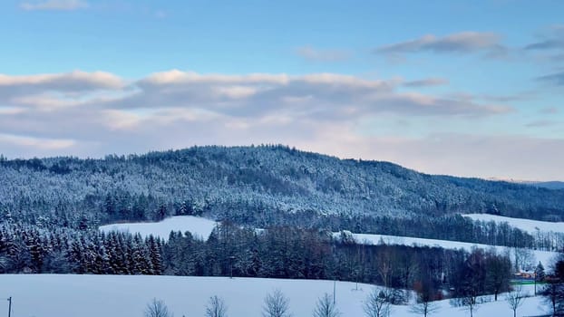 A beautifully peaceful and tranquil winter scene featuring hills blanketed with fresh snow under a clear blue sky