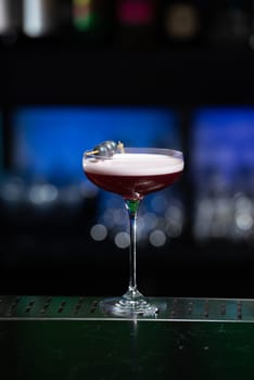 The blurred background features dark tones with hints of green and white bokeh lights, suggesting a stylish bar setting