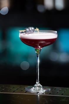 The blurred background features dark tones with hints of green and white bokeh lights, suggesting a stylish bar setting