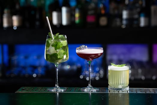 row of various colourfull alcoholic cocktails on a bar desk. Glasses of differen shapes on a fancy background