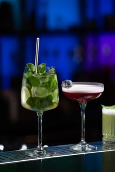 row of various colourfull alcoholic cocktails on a bar desk. Glasses of differen shapes on a fancy background