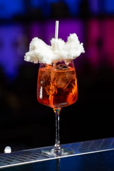 The background features a blurred mix of deep blue and purple hues, suggesting a modern bar or lounge atmosphere