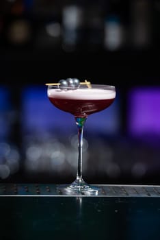 The blurred background features dark tones with hints of green and white bokeh lights, suggesting a stylish bar setting