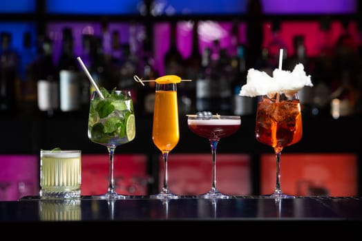 row of various colourfull alcoholic cocktails on a bar desk. Glasses of differen shapes on a fancy background