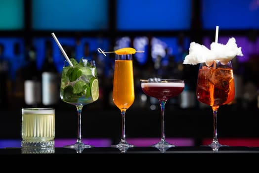 row of various colourfull alcoholic cocktails on a bar desk. Glasses of differen shapes on a fancy background