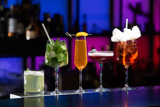 row of various colourfull alcoholic cocktails on a bar desk. Glasses of differen shapes on a fancy background