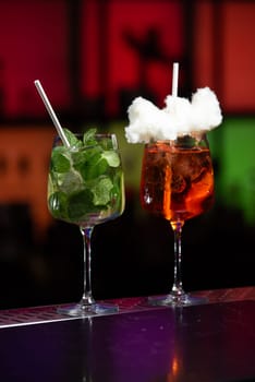 A blurred backdrop of red, green, and black suggests a lively bar or club setting.