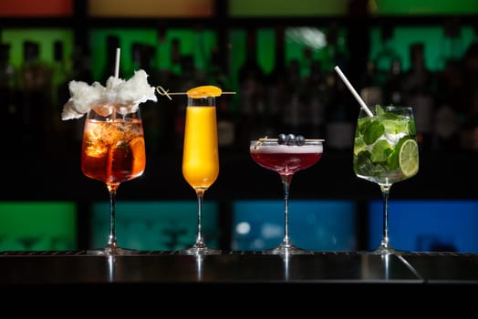 row of various colourfull alcoholic cocktails on a bar desk. Glasses of differen shapes on a fancy background
