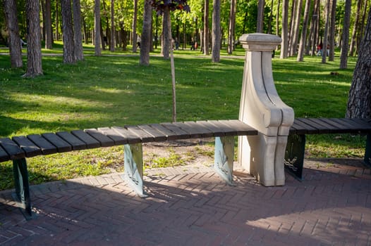 Minimalist wooden bench with stone elements in the park. Among the lush greenery in a quiet park. Cozy recreation area. Place to relax